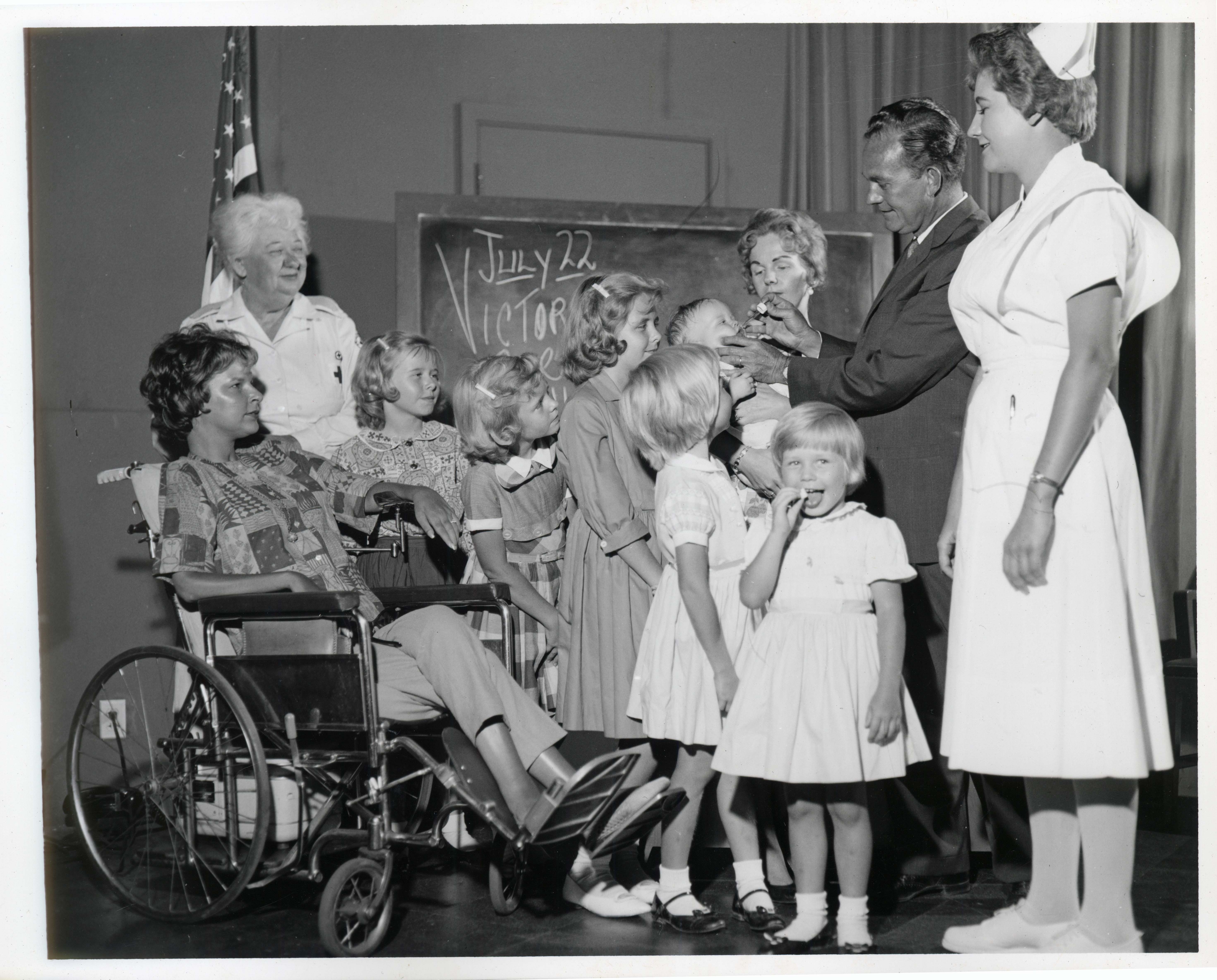 The little girl in the foreground seems to be thrilled that her vaccination comes in the form of a sugar cube and not a shot.